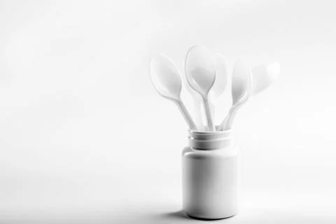 White Plastic Jar with Spoon on Light Background Stock Photos