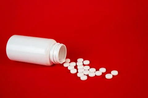 White plastic pill bottle tipped over with tablets falling out. Modern Stock Photos