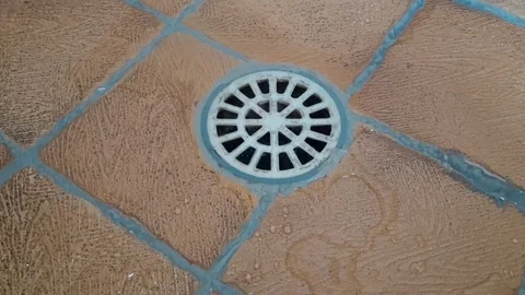 White plastic shower drain grate on wet textured tile footage Stock Footage 339249008