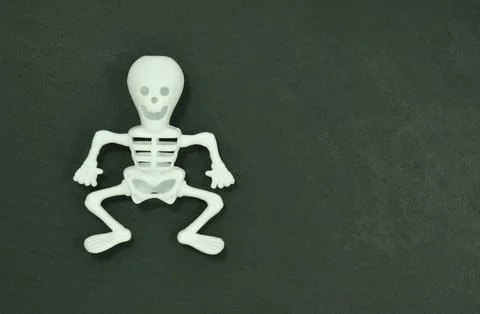 White plastic skeleton doll on a black chalkboard stone Stock Photos