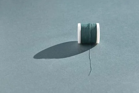 A white plastic spool of sewing thread in a beautiful emerald color lies with 스톡 사진