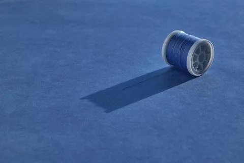 A white plastic spool of sewing thread in a beautiful blue color lies with an 스톡 사진