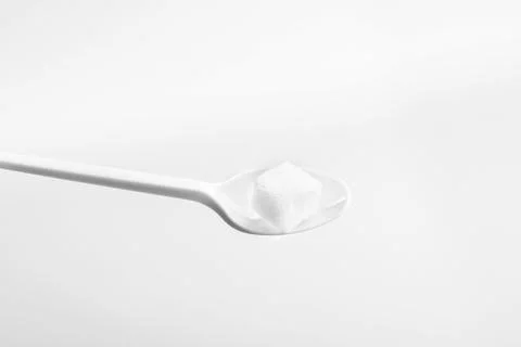 White Plastic Spoon with Sugar on White Background Foto stock