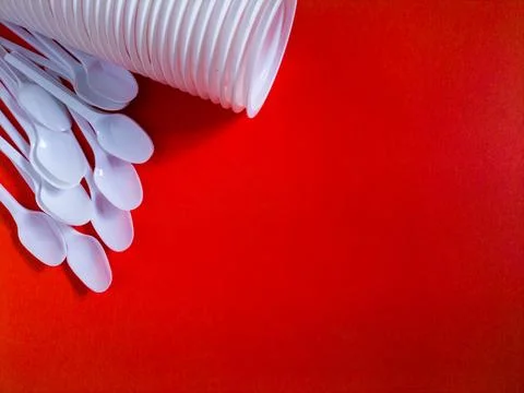 White plastic spoons on red background. Stock Photos