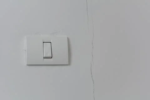 White plastic switch on a white wall. To the right of the switch there is a.. Foto stock