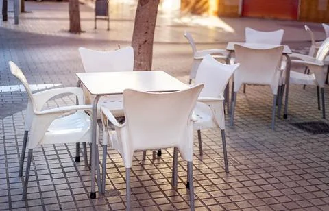 White plastic table surrounded by chairs on the terrace of a small cafe Stock Photos