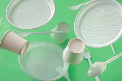 White plastic tableware levitating on green background Stock Photos
