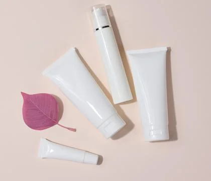 White plastic tubes, jars and other form of packaging for cosmetics on a be.. Stock Photos