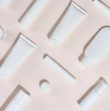 White plastic tubes, jars and other form of packaging for cosmetics on a be.. Stock Photos
