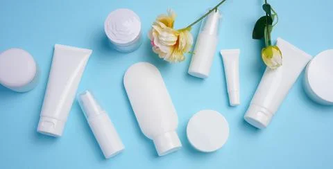 White plastic tubes, jars, and containers for cosmetic products on a blue b.. Stock Photos