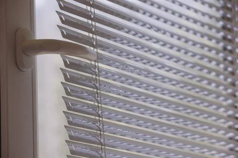White plastic window frame with handle and modern horizontal blinds Stock Photos