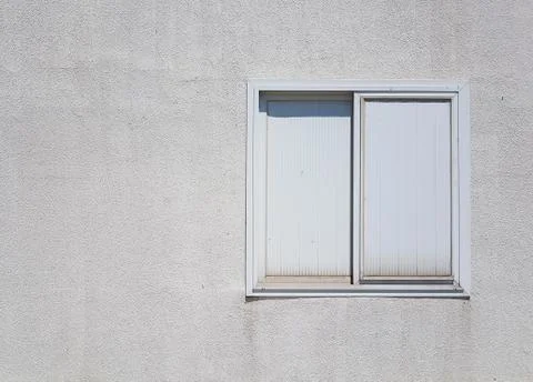 White plastic window on rough white concrete wall Фото