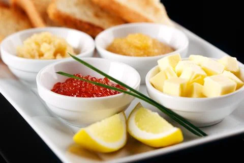 On a white plate of assorted with red white and pike caviar served baguette a Stock Photos