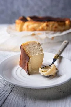 White plate with bitten portion of basque burnt cheesecake and vintage spoon Fotos Stock
