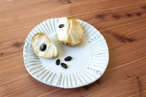 White plate centered with two sections of a ripe cherimoya fruit Annona Stock Photos