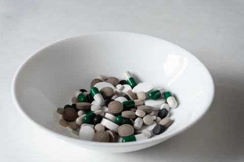 White plate with Different tablets and pills at white background Foto stock