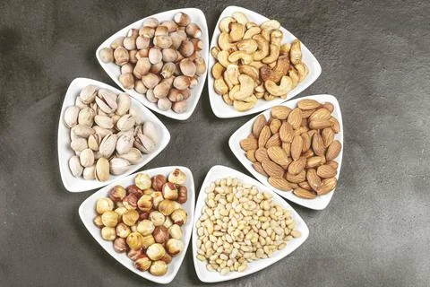 White plate featuring a various nuts and peanuts, including almonds, cashews, an Foto stock