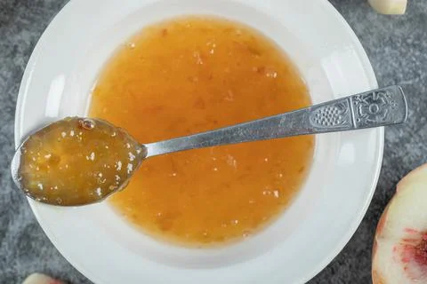 A white plate full of peach jam and spoon Stock Photos