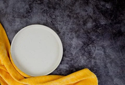 White plate on gray surface with yellow napkin, copy space Stock Photos