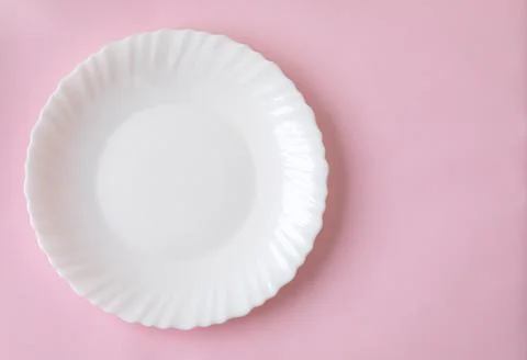 White plate on a light pink surface background Stock Photos