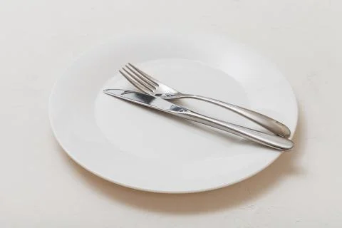 White plate with parallel knife, spoon on white Stock-Fotos