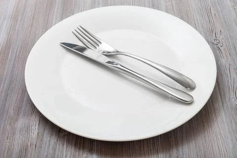 White plate with parallel knife, spoon on gray food concept - white plate ... Fotos Stock