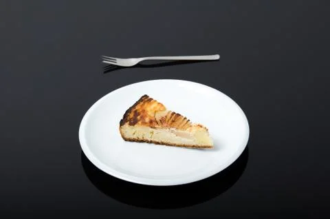 White plate with piece of pear pie on and a fork beside isolated on dark back Stock Photos