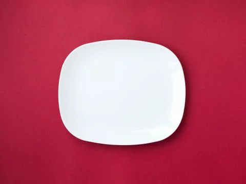 White plate on red colored background Stock Photos