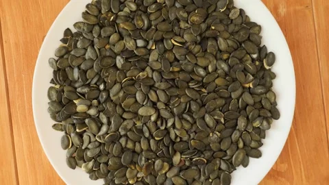 White plate of rotating shelled pumpkin seeds Stock Footage 337441405
