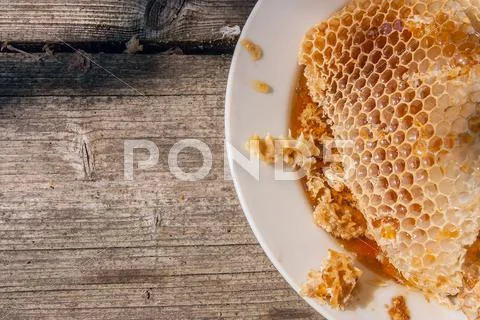 White plate with section of wax honeycomb from beehive on the vintage wooden Stock Photos