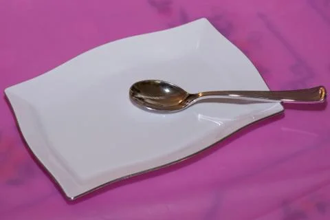 White plate with silver spoon Stock Photos