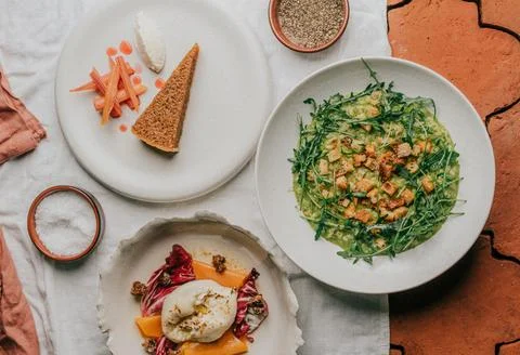 A white plate with a slice of cake and a bowl of salad Stock Photos