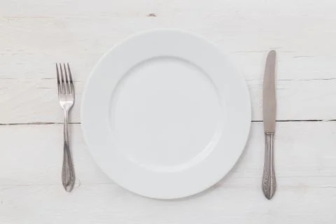 White plates and silverware on a light wood Stock Photos