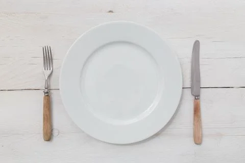 White plates and silverware on a light wood Stock Photos