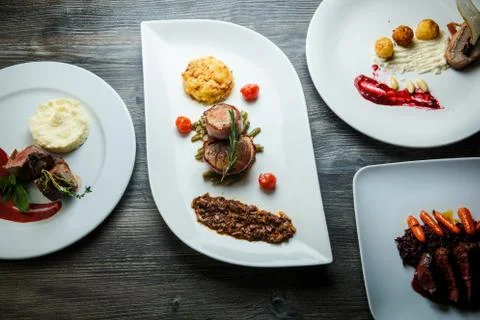 White plates with different dishes with meat, mashed potato, and wild rice on Stock Photos