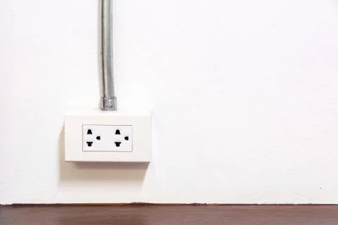 White plug socket with Electrical conduit pipe on wall Stock Photos