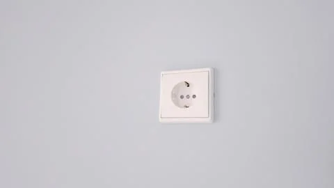 A white plug socket is hanging on a wall Stock Photos