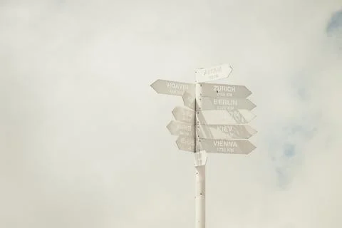 White pointer with multiple arrow-heads on cloudy sky background, city names Stock Photos