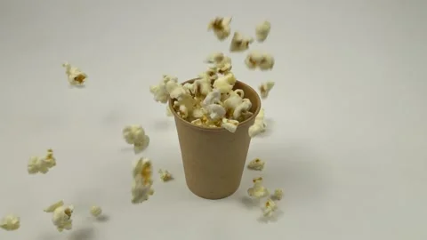 White popcorn fall into a paper cup on a white table, slow motion Stock Footage 220848192