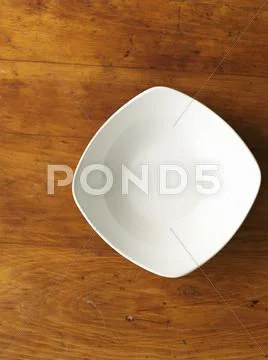 A white porcelain bowl on a wooden surface (seen from above) Stock Photos