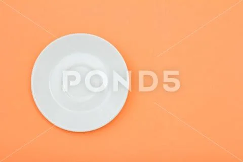 White porcelain saucer on peach color background. Stock Photos