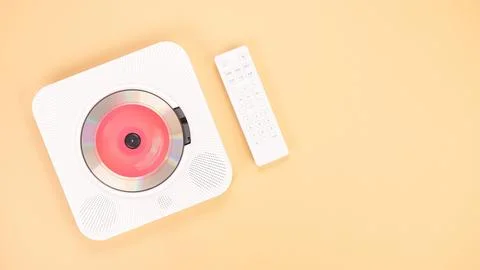 White portable CD player with remote control isolated on peach background. Stock Photos
