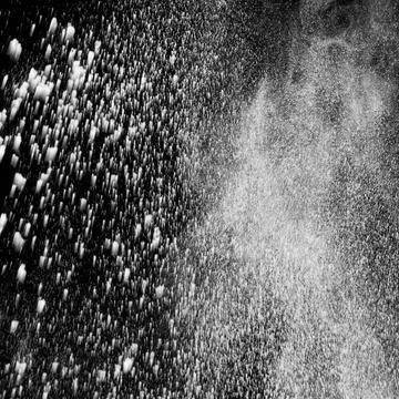 White powder explosion cloud against black background.White dust particles sp Stock Photos