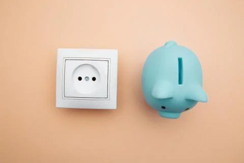 White power socket and blue piggy bank. Power energy economy Stock Photos