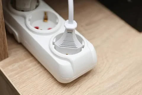 White power strip with plug inserted on wooden surface Stock Photos