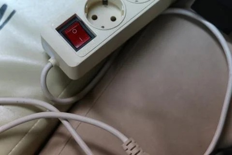 White Power Strip with Red On Off Switch and Electric Cables on Leather Surf Фото