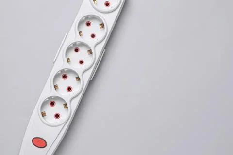 White power strip with six electrical outlets on a gray background Stock Photos