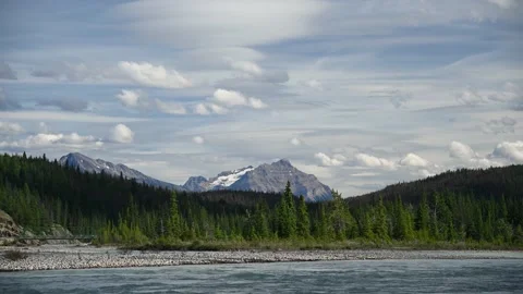 White puffy and wispy clouds drift through a late afternoon sky above a mountain Stock Footage 146467257