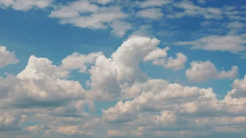 White puffy clouds drifting across a bright blue sky during a sunny afternoon 스톡 동영상 341562924