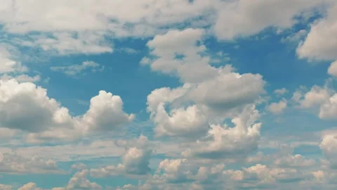 White puffy clouds drifting across a bright blue sky during a sunny afternoon Stock-Footage 341562926